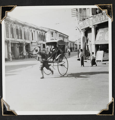 Runner and rickshaw, buildings and people in background.