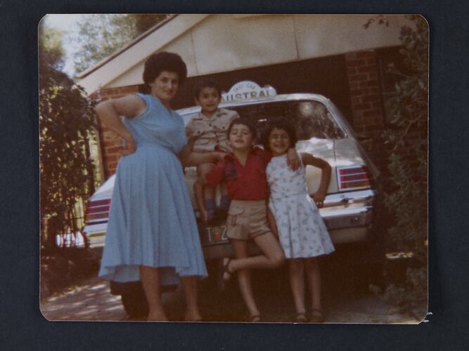 Portrait of a woman and three children standing in front of a taxi