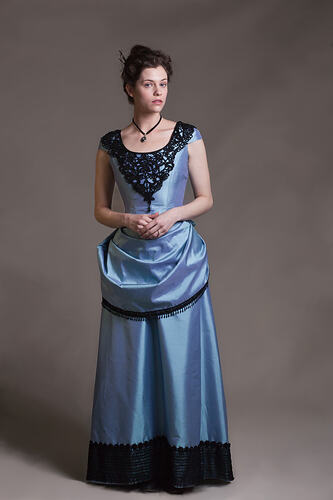 Woman wearing a light blue bodice, skirt and bustle cover