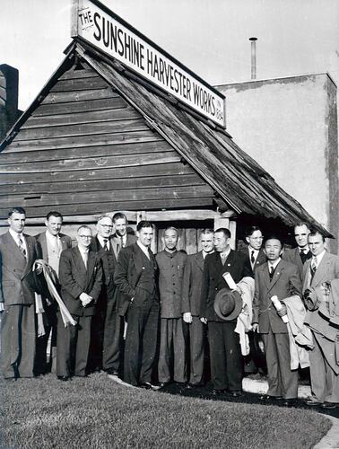 Men standing in front of timber building.