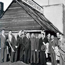 Men standing in front of timber building.