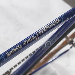 Detail of blue metal bicycle crossbar with white decorative motifs.