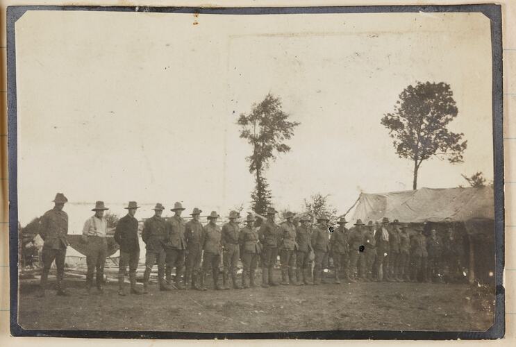 A row of soldiers standing outside a military tent.