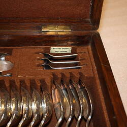 Open wooden cutlery box. Detail of soup ladle and spoons.