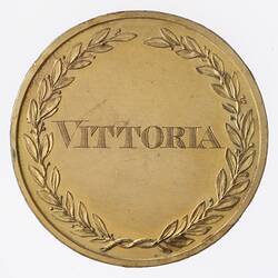 Round gold medal with laurel wreath framing engraved word 'VITTORIA.'