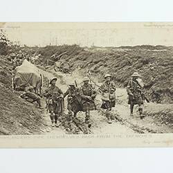 Men in kilts walking along sunken pathway in battleground.