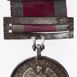 Tarnished silver medal with Victory seated, wings spread, holding a palm and olive branch. Red ribbon.