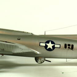 Silver model aeroplane. Profile facing left.