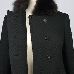 Black woollen double-breasted coat with fur collar and six plastic buttons. Bodice detail.