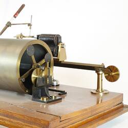 Scientific instrument on wooden base with brass cylinder, side view.