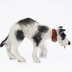 Black and white dog figurine with red collar and tongue. Profile.