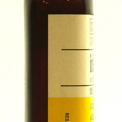 Side of brown glass bottle with white cap.