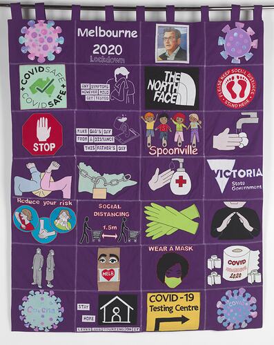 Purple fabric applique wall hanging with 27 square sections featuring multicoloured images and symbols.