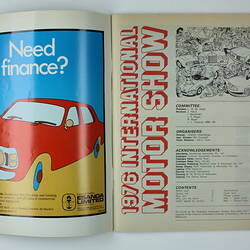 Open double page of motor show catalogue showing colour printed illustration of a red car, and extensive text.
