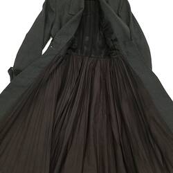 Long coat made from a grey woollen fabric. Laid flat. Open, black silk lining.