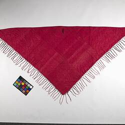 Triangular shawl with vivid pink on one side. Has pink fringing.