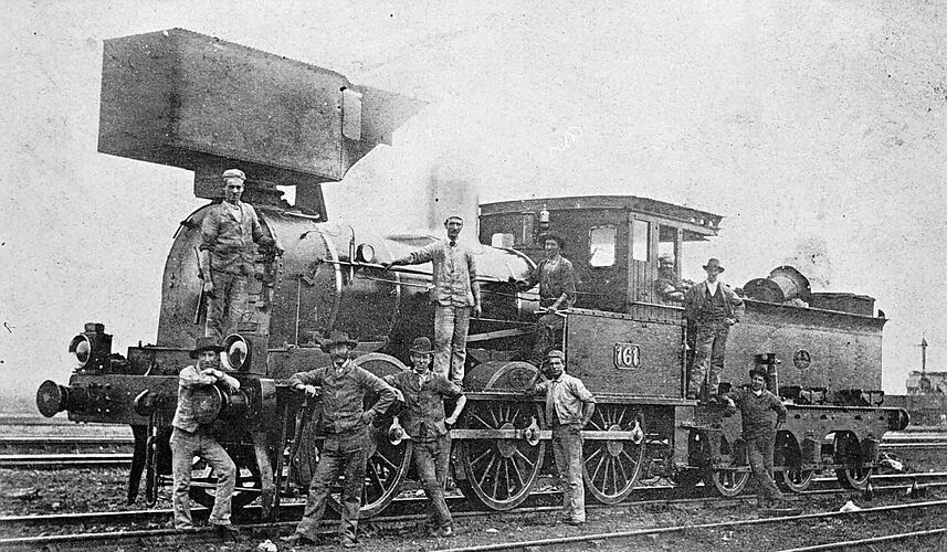 [Men posing with an old R-class steam locomotive which has been fitted with a smoke deflector, Victoria, circa 1870.]