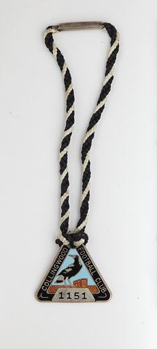 Triangular medal with magpie and black, blue and brown enamel. Black and white twined cord. Silver text.