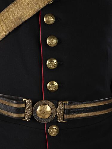 Detail of navy officer's jacket with brass buttons. Gold and navy belt.