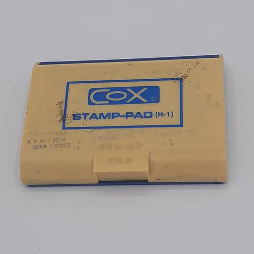 Plastic stamp pad with blue logo and text.
