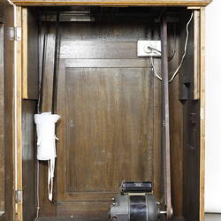 Wooden clock, detail of inside with open lower cabinet door.