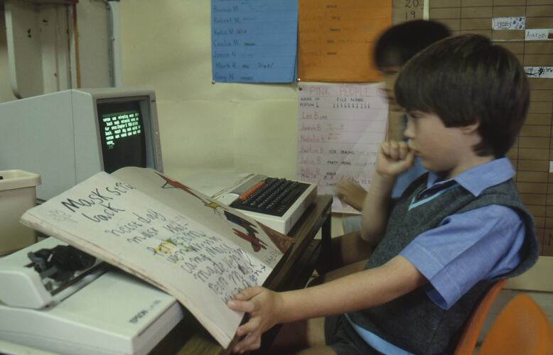 A young boy working on a computer in a classroom.