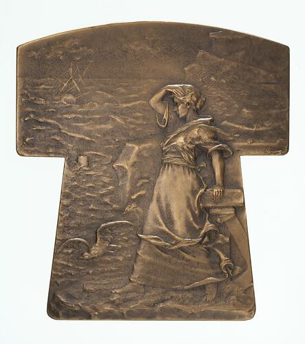 Bronze tau (t-shaped) medal, woman looking out to a rough sea at a shipwreck.