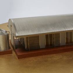 Model of a house with an arched roof, corrugated iron and wide expanses of glass.