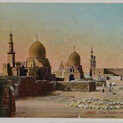 Mosque-like tombs with domed roofs in desert setting. Orange and blue sky.