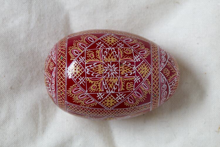 Egg, hand painted red background with yellow, white and pink intricate diamond design.