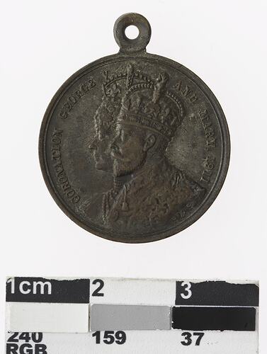 Round medal with bust of a man and woman wearing crowns in profile and text.