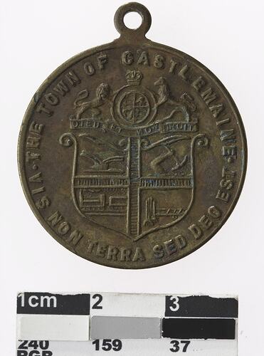 Round bronze coloured medal with coat of arms, text surrounding.