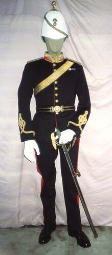 Mannequin wearing black military uniform with white helmet, white gloves and sword, front view.