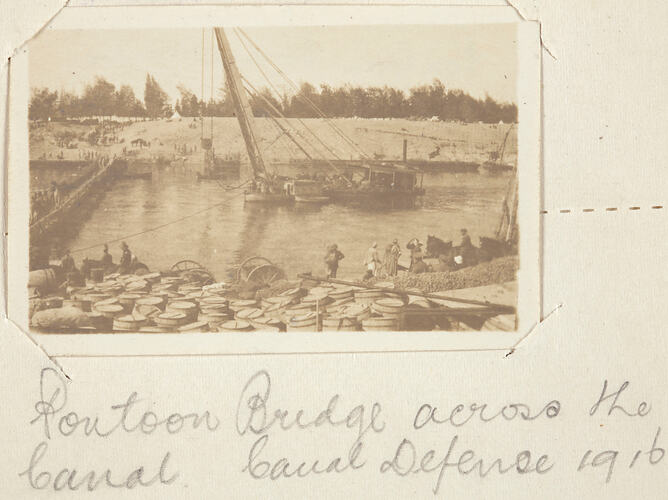 Boat on canal with bridge on left and people on both banks.