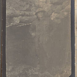 Soldier wearing a helmet standing in a trench.