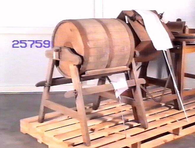 Wooden tumble action barrel butter churn mounted in a wooden frame with four legs.