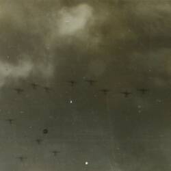 Planes flying in formation in the sky, ocean below.
