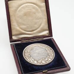Open wooden case with silver medal.