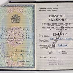 Open passport with white pages and black printed text. Blue handwriting. Stamped.