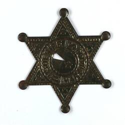 Front of six pointed toy metallic sheriff badge.