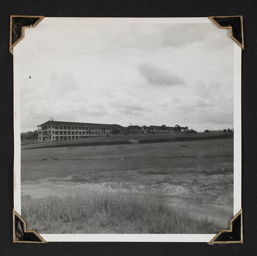 Three story building in distance, clear sloping landscape in foreground.