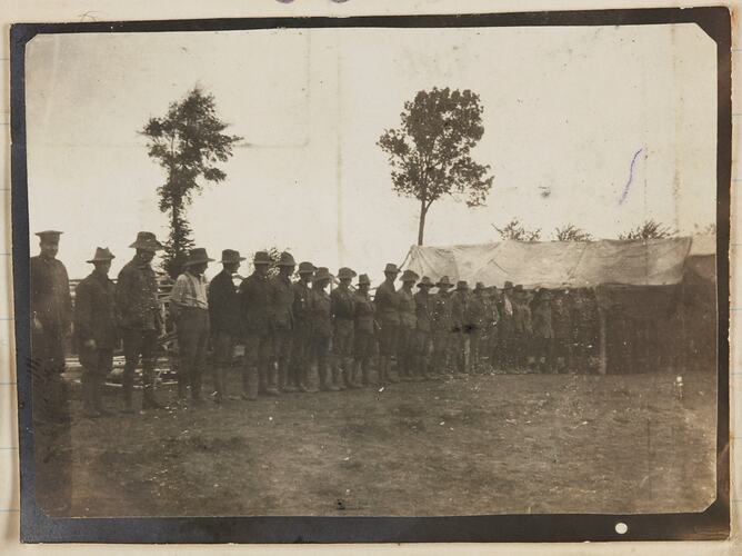 A row of soldiers standing outside a military tent.