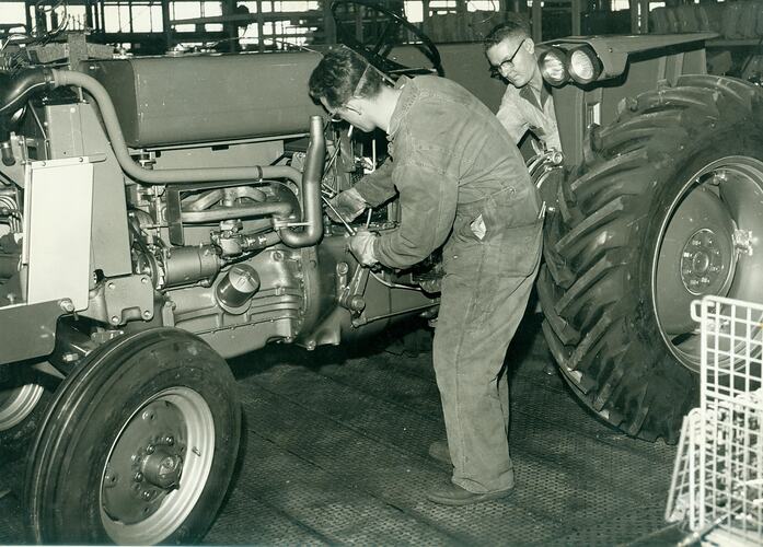 2 men on tractor assembly line.
