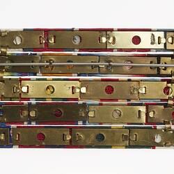 Back of mounted medal ribbons on five horizontal bronze coloured bars, joined by pin.