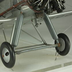 Silver model biplane model with red, white, blue rondels on wings and fuselage. Silver propeller. Wheels detail.
