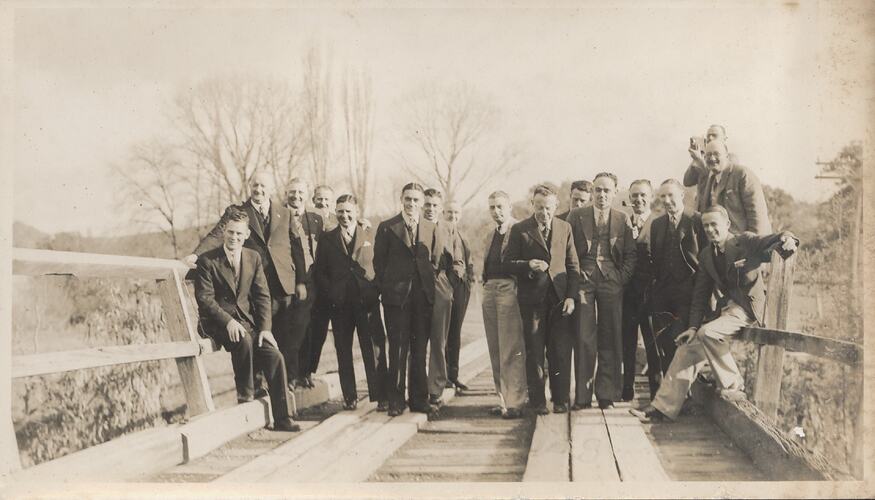 Men in suits on railway bridge.