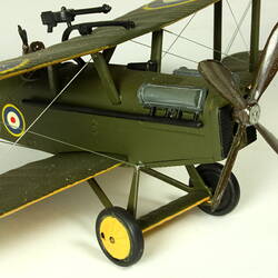 Dark green model airplane. Circle pattern on top on each wing. Front propeller detail.