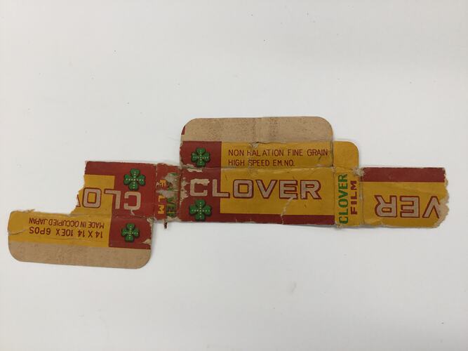 Flattened torn yellow and red cardboard box with four leaf clover logo.