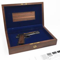 Wooden case with blue lining. Contains pistol.