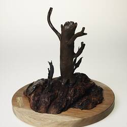Metal and wood tree-shaped sculpture on round base.